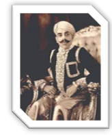 A person with a mustache sitting on a chairDescription automatically generated with medium confidence